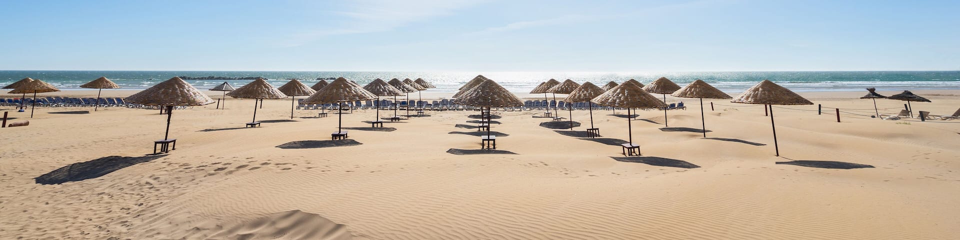 Beach umbrellas on the the beautiful unique sand beach. Vacation and summer holidays concept. Banner and panoramic edition.