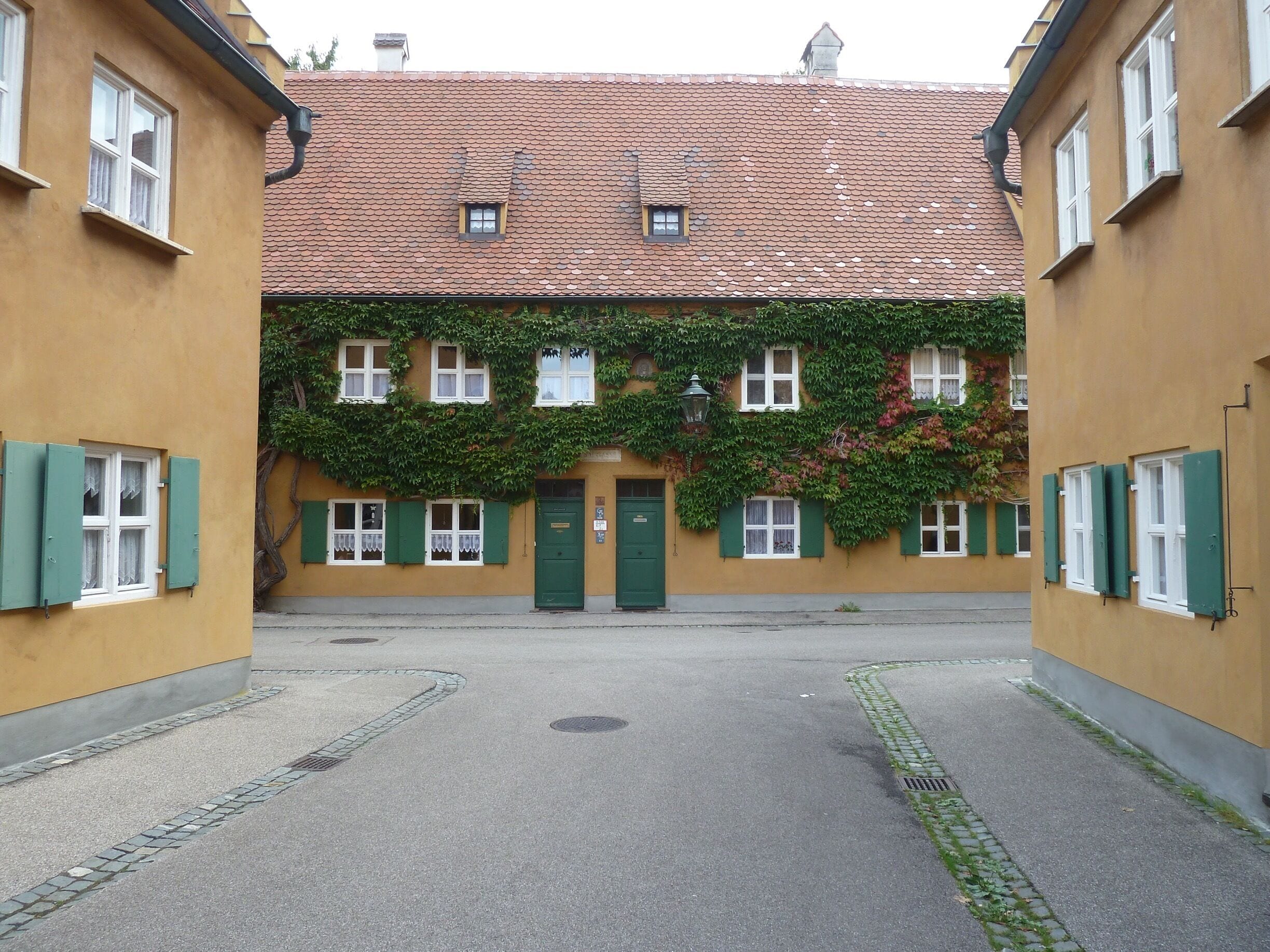 On an unscheduled stop in Augsburg, Germany, we found the very special place of The Fuggerei. Well worth a visit. The museum is small but informative.  You can also see inside one of the houses.

Mozart’s father lived here.

Wikipedia says:
The Fuggerei is the world's oldest social housing complex still in use. It is a walled enclave within the city of Augsburg, Bavaria. It takes its name from the Fugger family and was founded in 1516 by Jakob Fugger the Younger (known as "Jakob Fugger the Rich") as a place where the needy citizens of Augsburg could be housed. By 1523, 52 houses had been built, and in the coming years the area expanded with various streets, small squares and a church. The gates were locked at night, so the Fuggerei was, in its own right, very similar to a small independent medieval town. It is still inhabited today, affording it the status of being the oldest social housing project in the world.