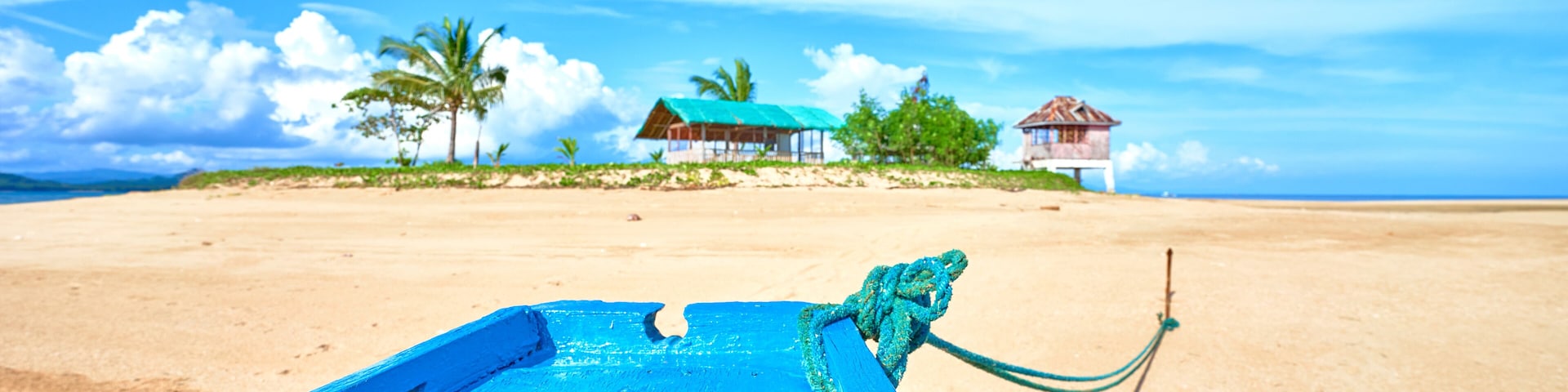 A beach with a blue boat, a starfish, and a rope tied to a post.
