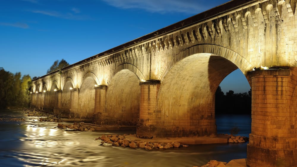 A stone bridge over a river at dusk.