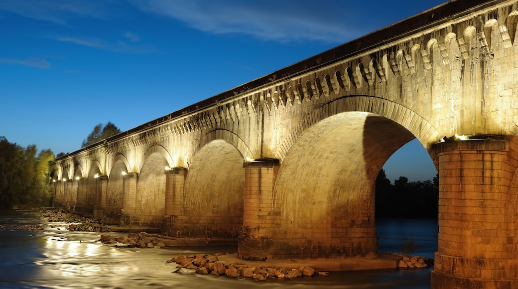 Uma ponte de pedra sobre um rio ao entardecer.