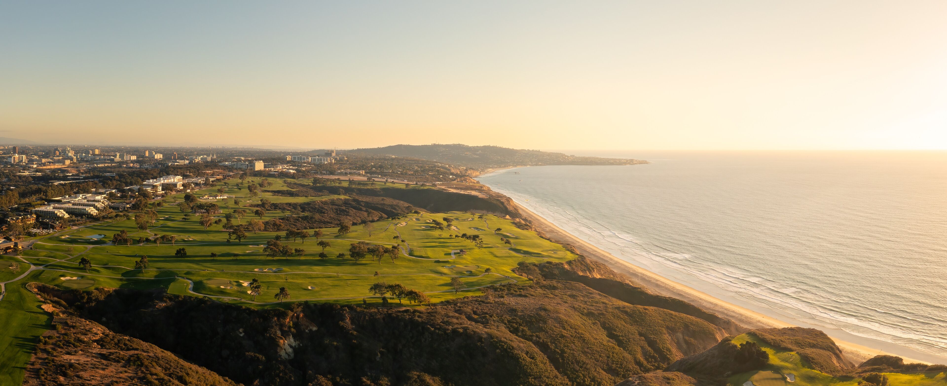 A coastal cityscape with a golf course and a beach.