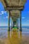 A pier extending into the ocean with clear blue water and a sandy beach.