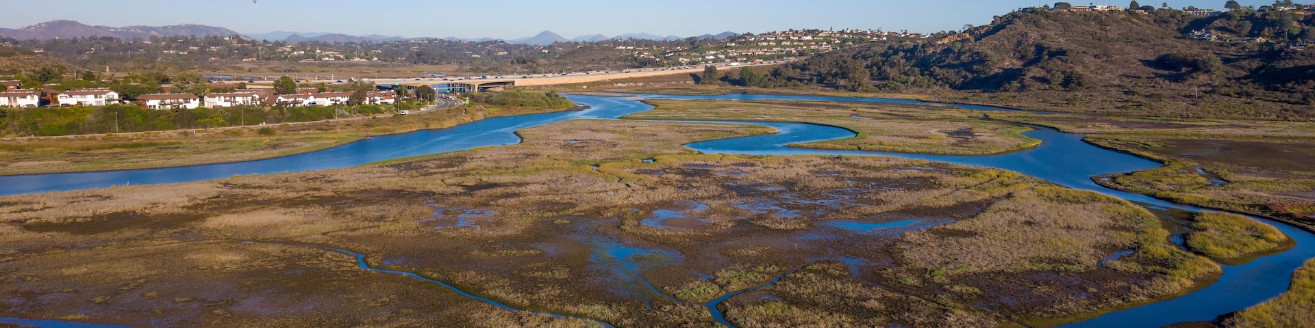 Un río serpenteando a través de un paisaje pantanoso con un pueblo al fondo.