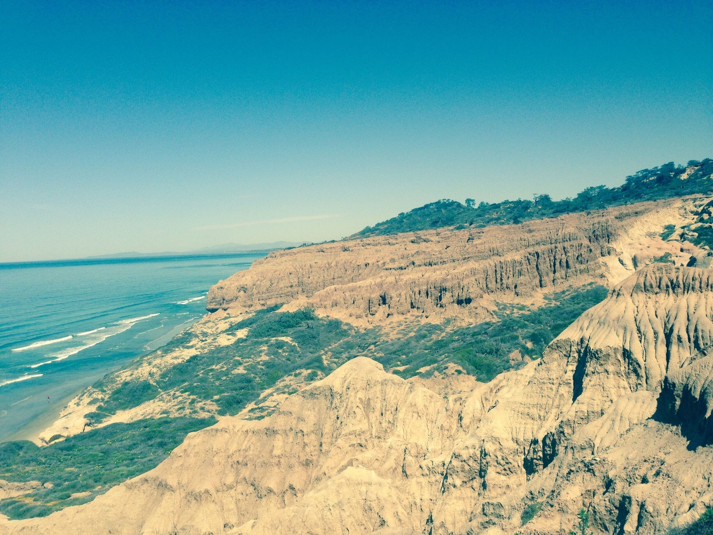 A coastal landscape with cliffs, greenery, and the ocean.