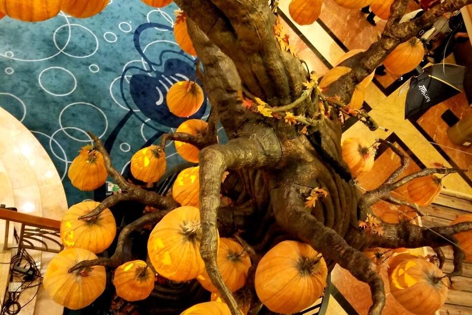Ein großer künstlicher Baum mit Kürbissen und Herbstlaub.