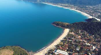 A coastal town with a beach, mountains, and a clear blue sea.