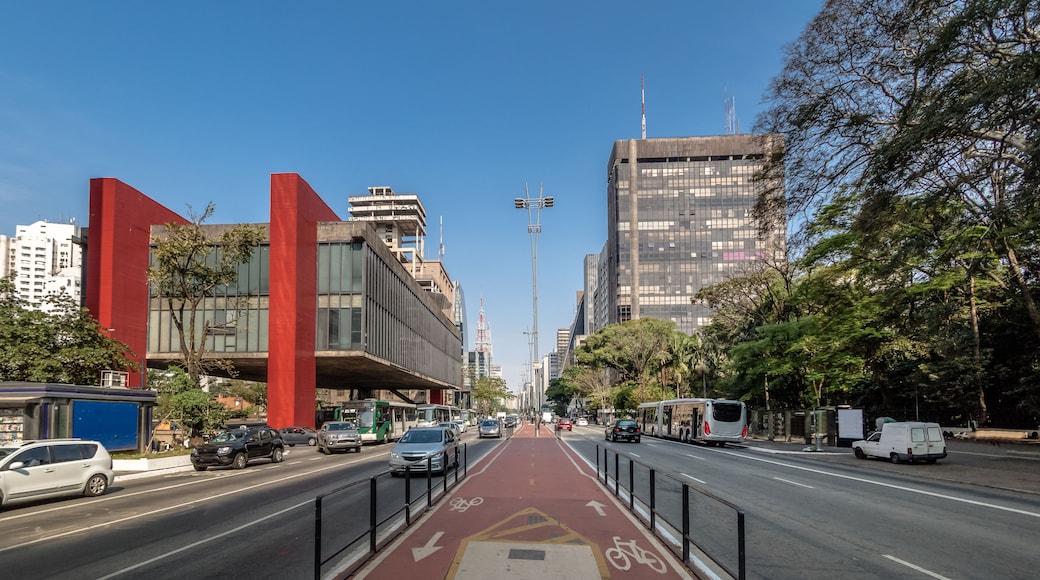 A city street with a bike lane, tall buildings, and a clear blue sky.