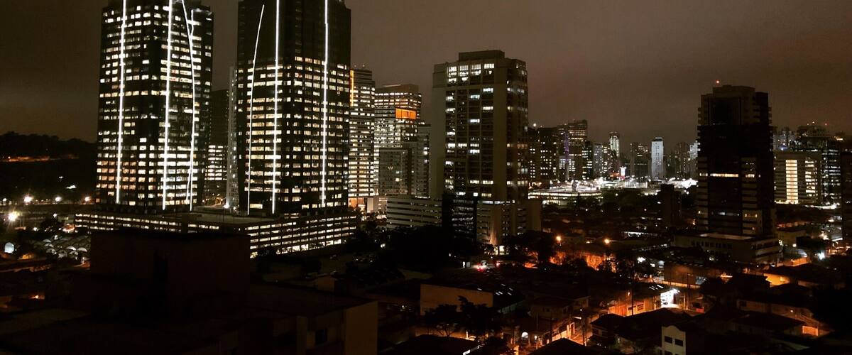 A nighttime cityscape with illuminated skyscrapers and a dense urban area.