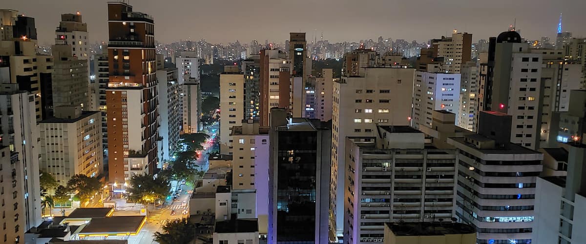 A cityscape at night with tall buildings, streetlights, and illuminated signs.