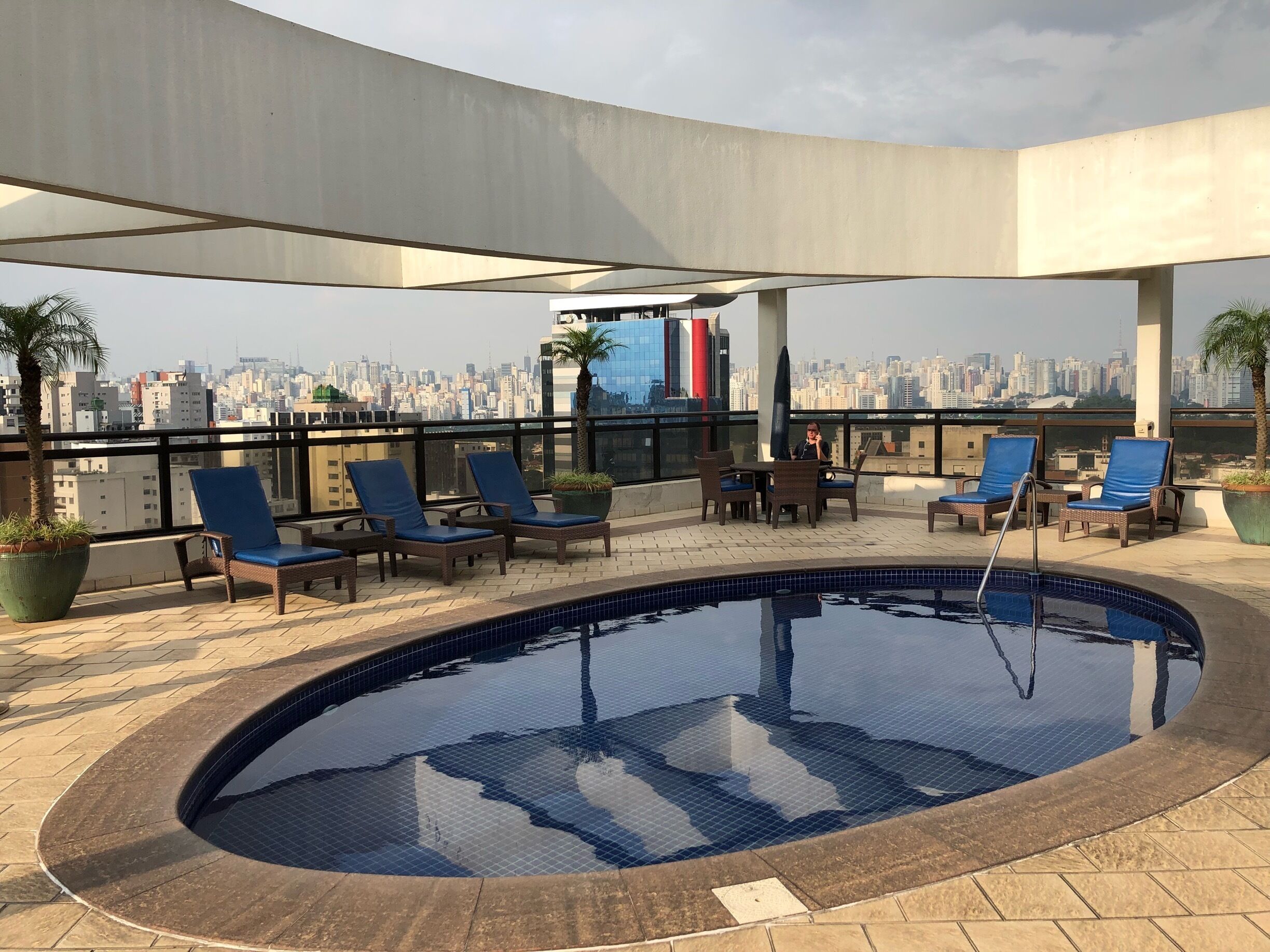 Piscina en la azotea con sillones de descanso y vista panorámica de la ciudad.