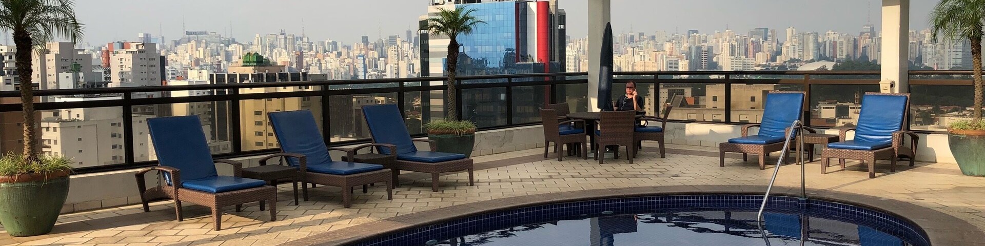Piscina en la azotea con sillones de descanso y vista panorámica de la ciudad.