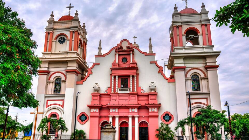 A church with two bell towers, a central dome, and a clock on each tower.