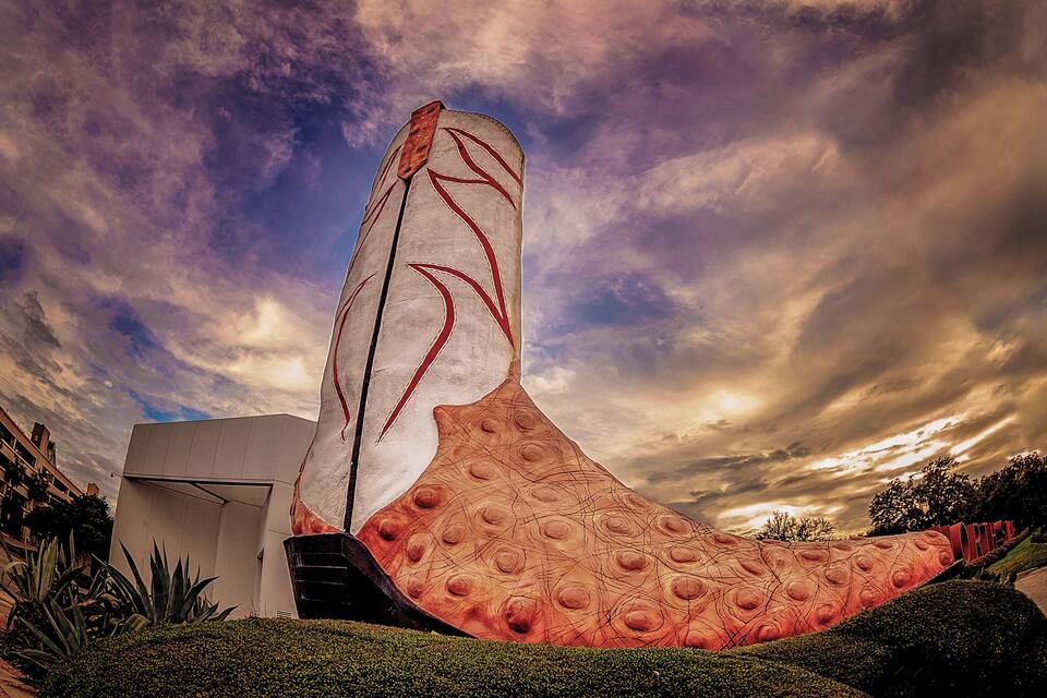 A large, abstract sculpture with a flowing design, set against a dramatic sky.