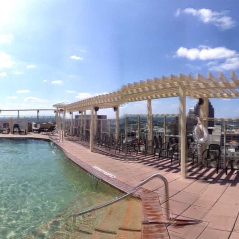 Uma piscina no terraço com água cristalina, uma pérgula e cadeiras.