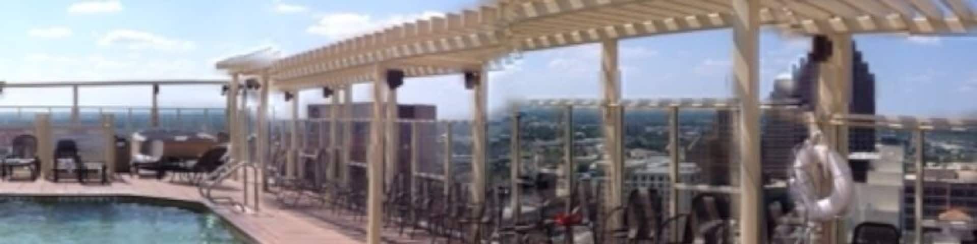 Uma piscina no terraço com água cristalina, uma pérgula e cadeiras.