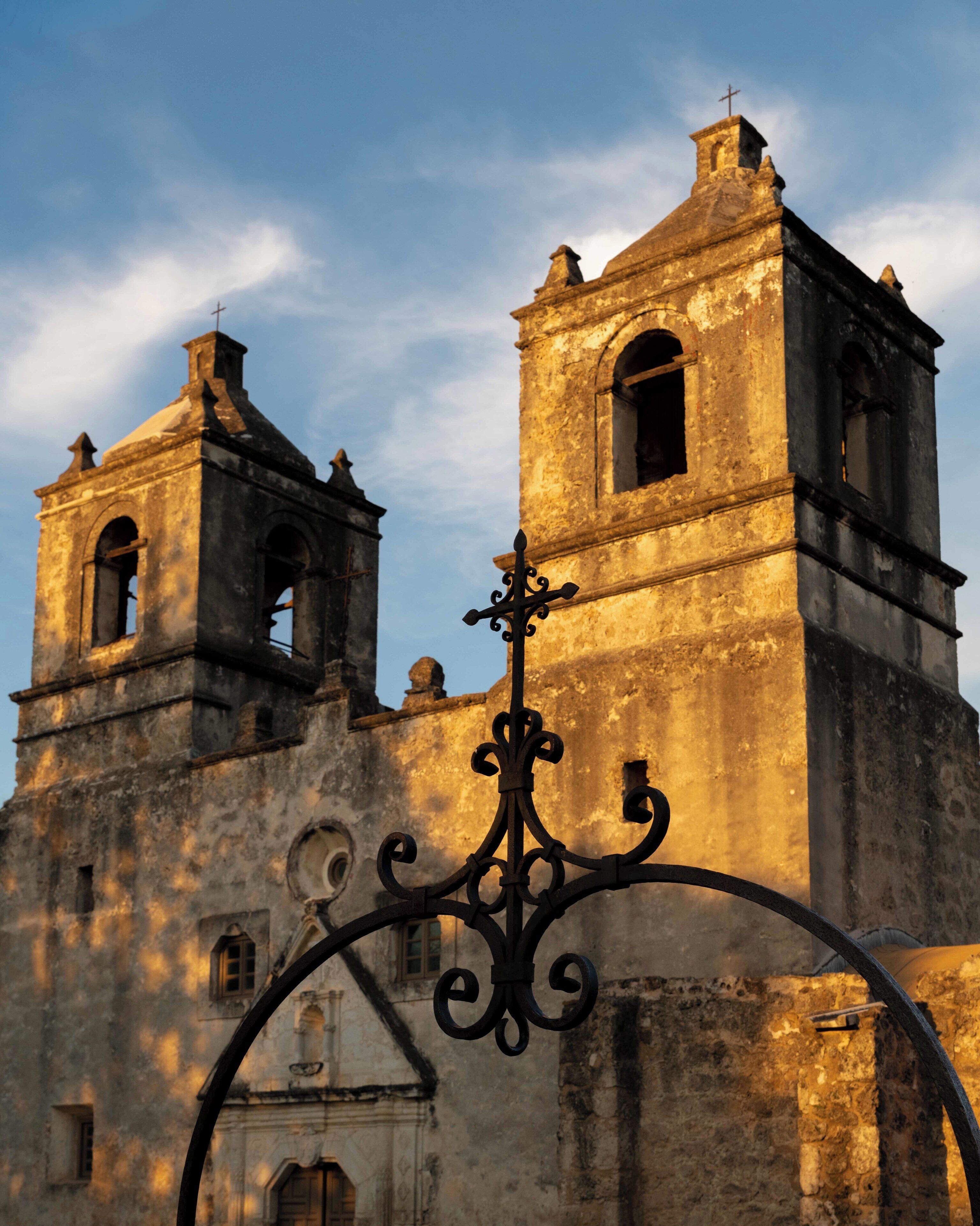 A historic church with two bell towers and a wrought iron gate.