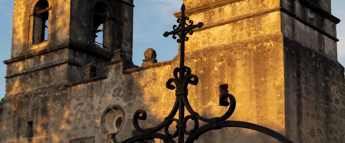 A historic church with two bell towers and a wrought iron gate.