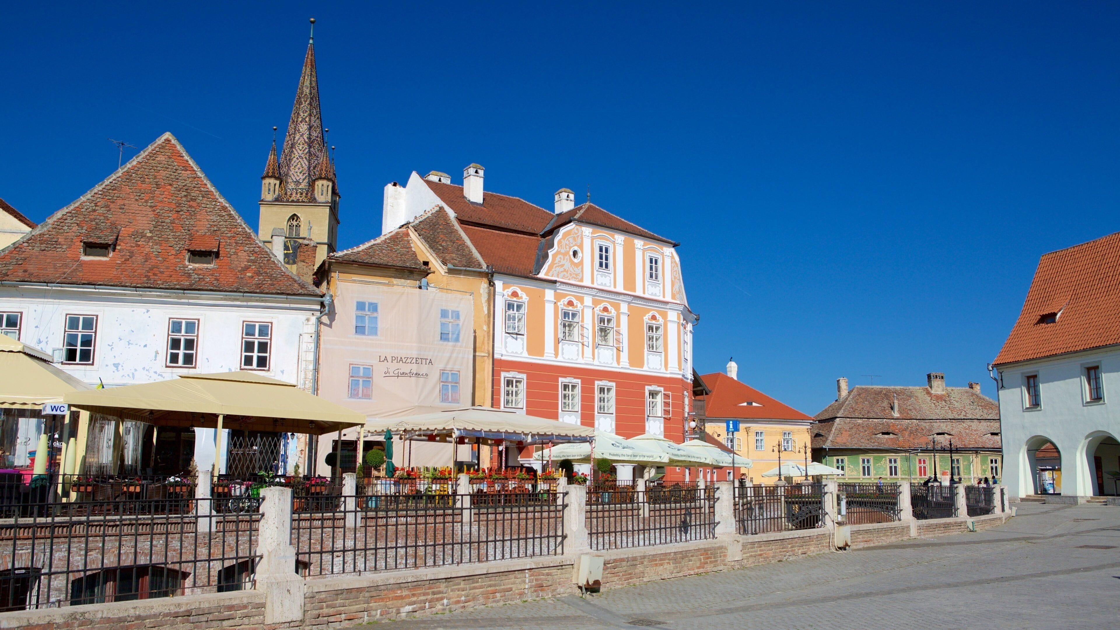A historic town square with colorful buildings, a church tower, and a market area.