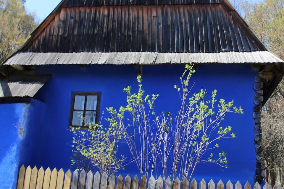 A rustic wooden house with a blue exterior and a wooden picket fence.