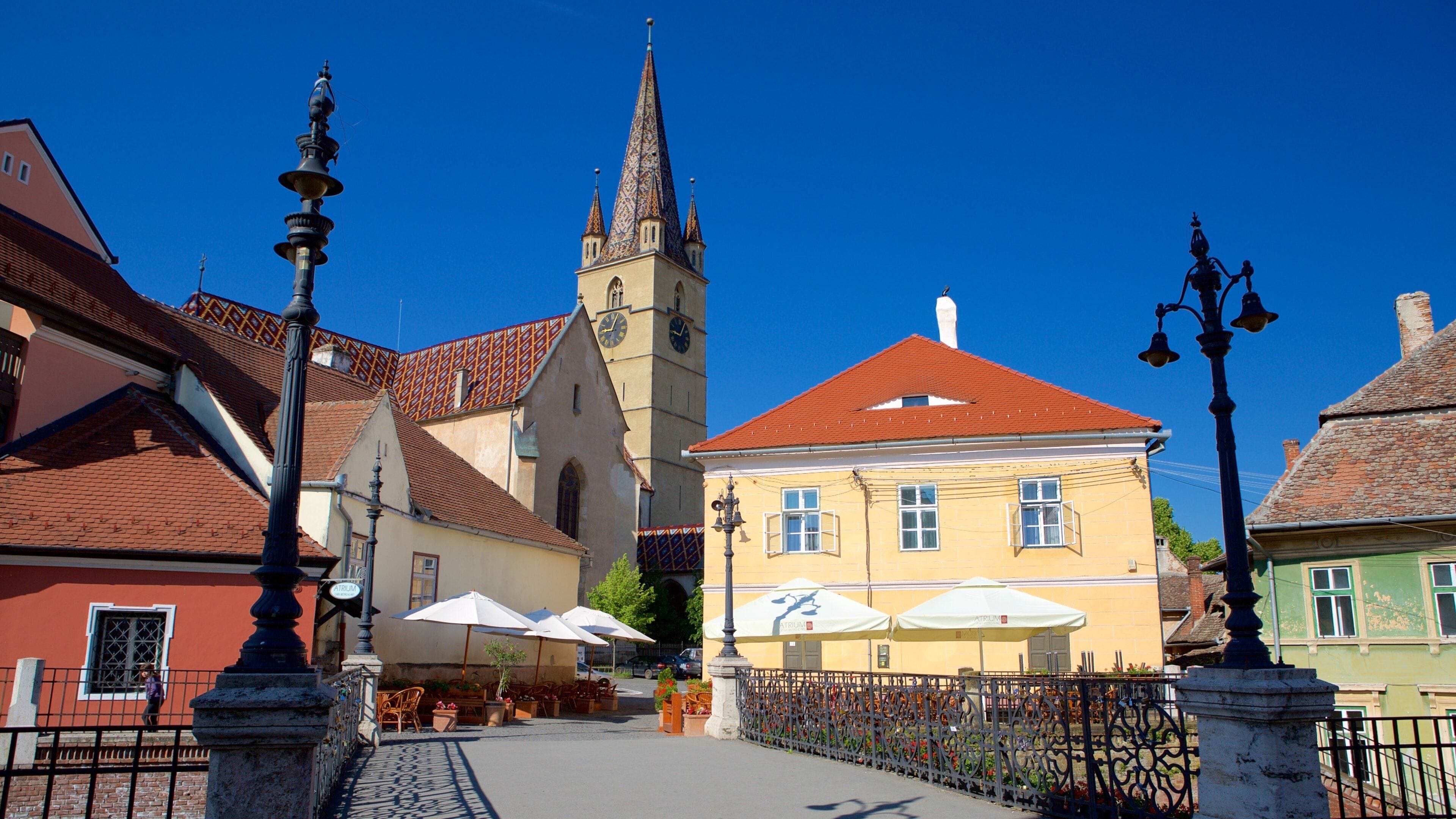 A historic town square with a church, a yellow building, and outdoor seating.