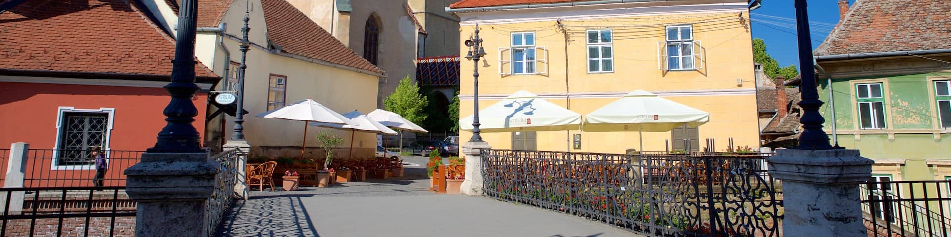 A historic town square with a church, a yellow building, and outdoor seating.