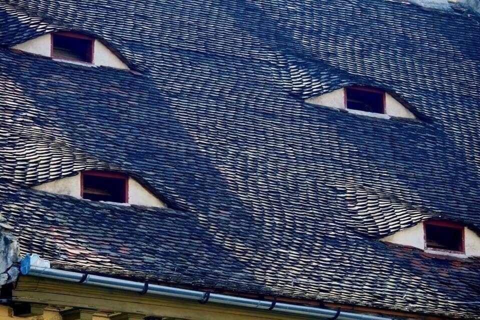 Um edifício com telhado telhado e várias janelas pequenas.