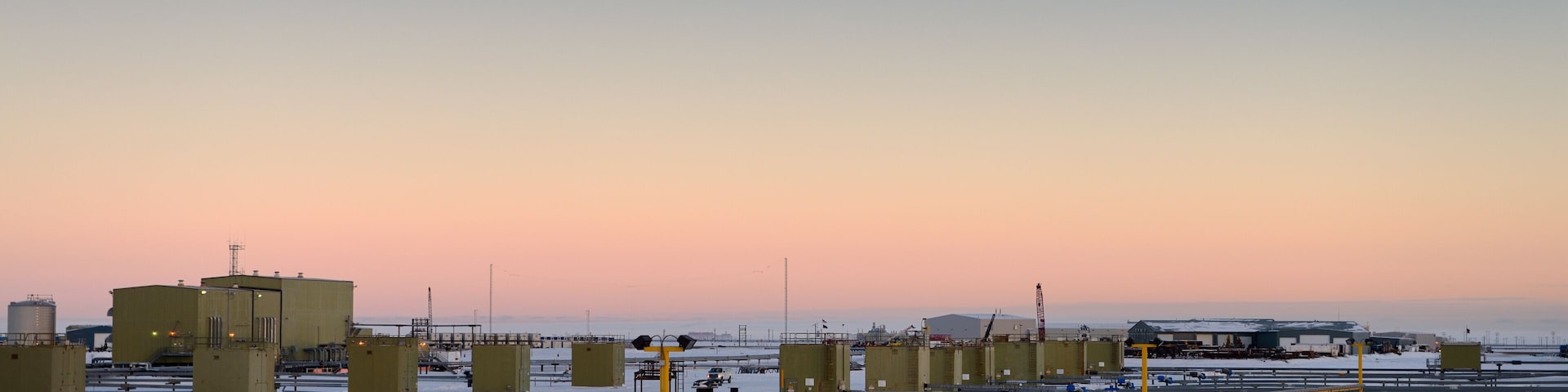 Un área industrial cubierta de nieve, con tanques de almacenamiento grandes y camiones.