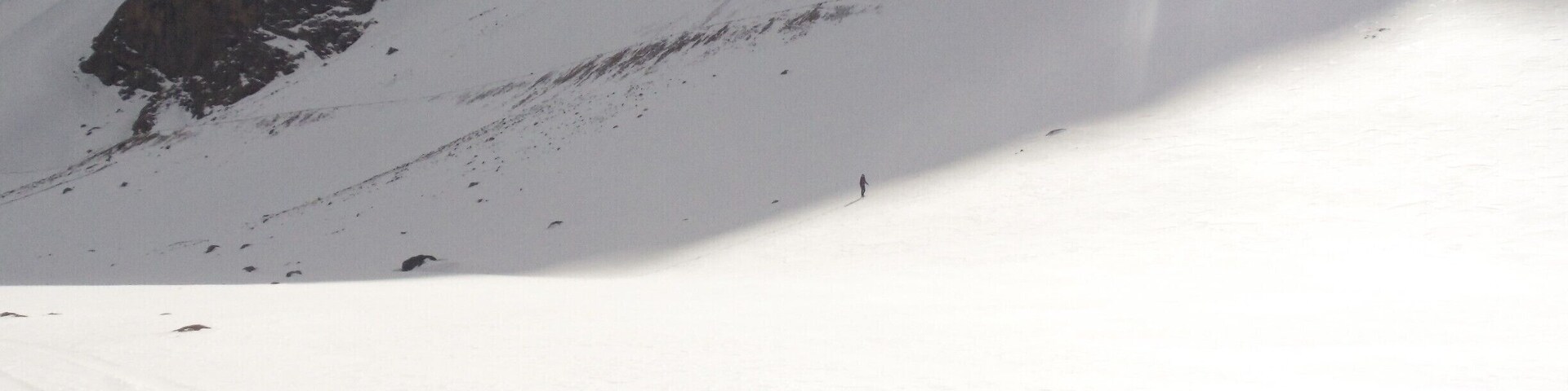 Una ladera nevada de montaña con una persona esquiando.
