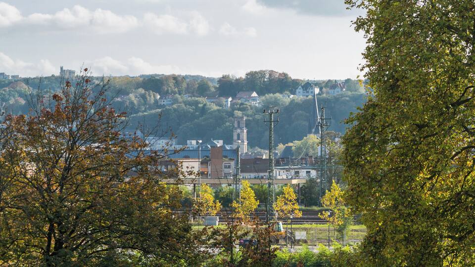 A town with a train station, surrounded by trees and hills.