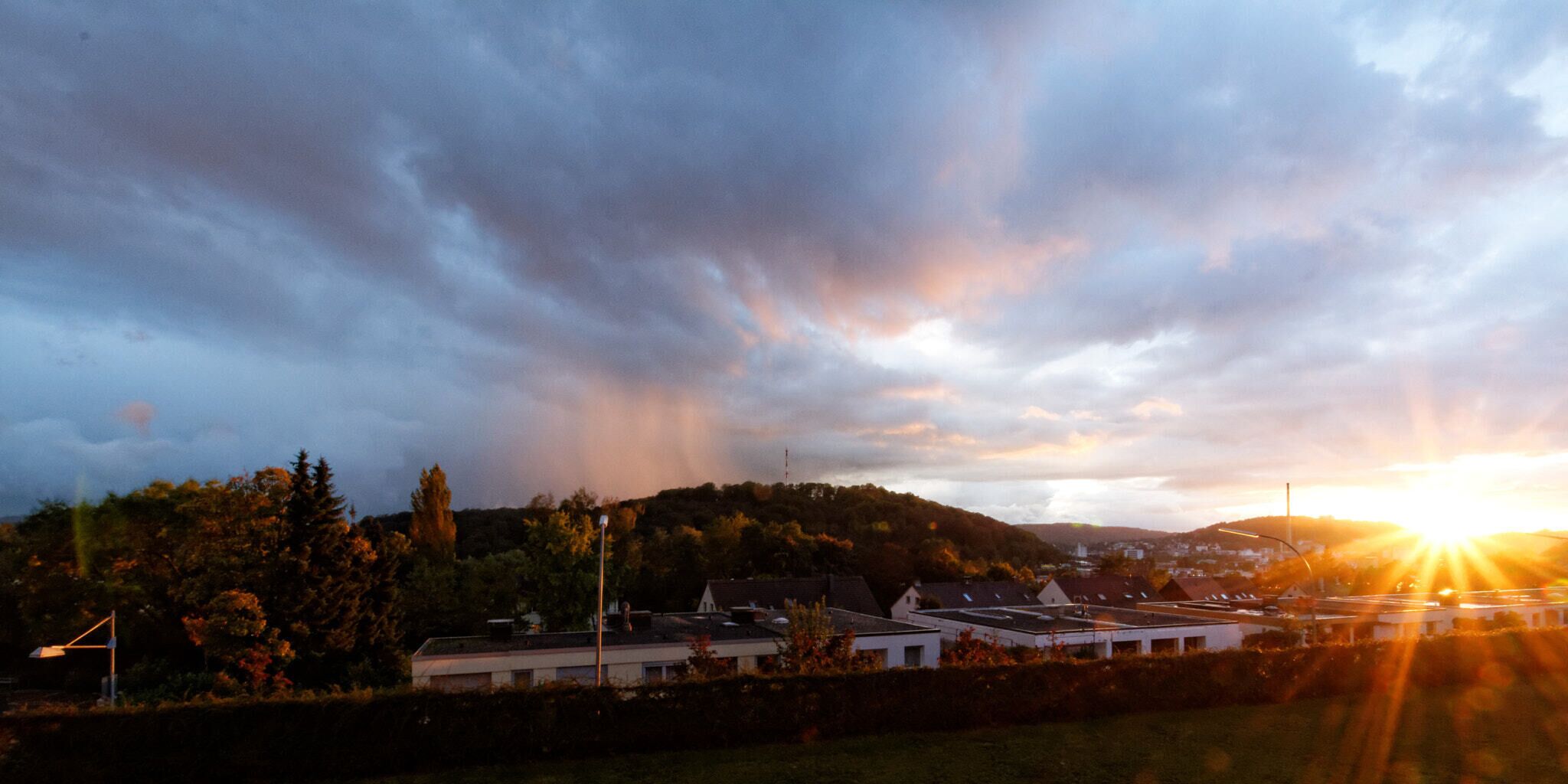 A sunset over a town with buildings and hills.