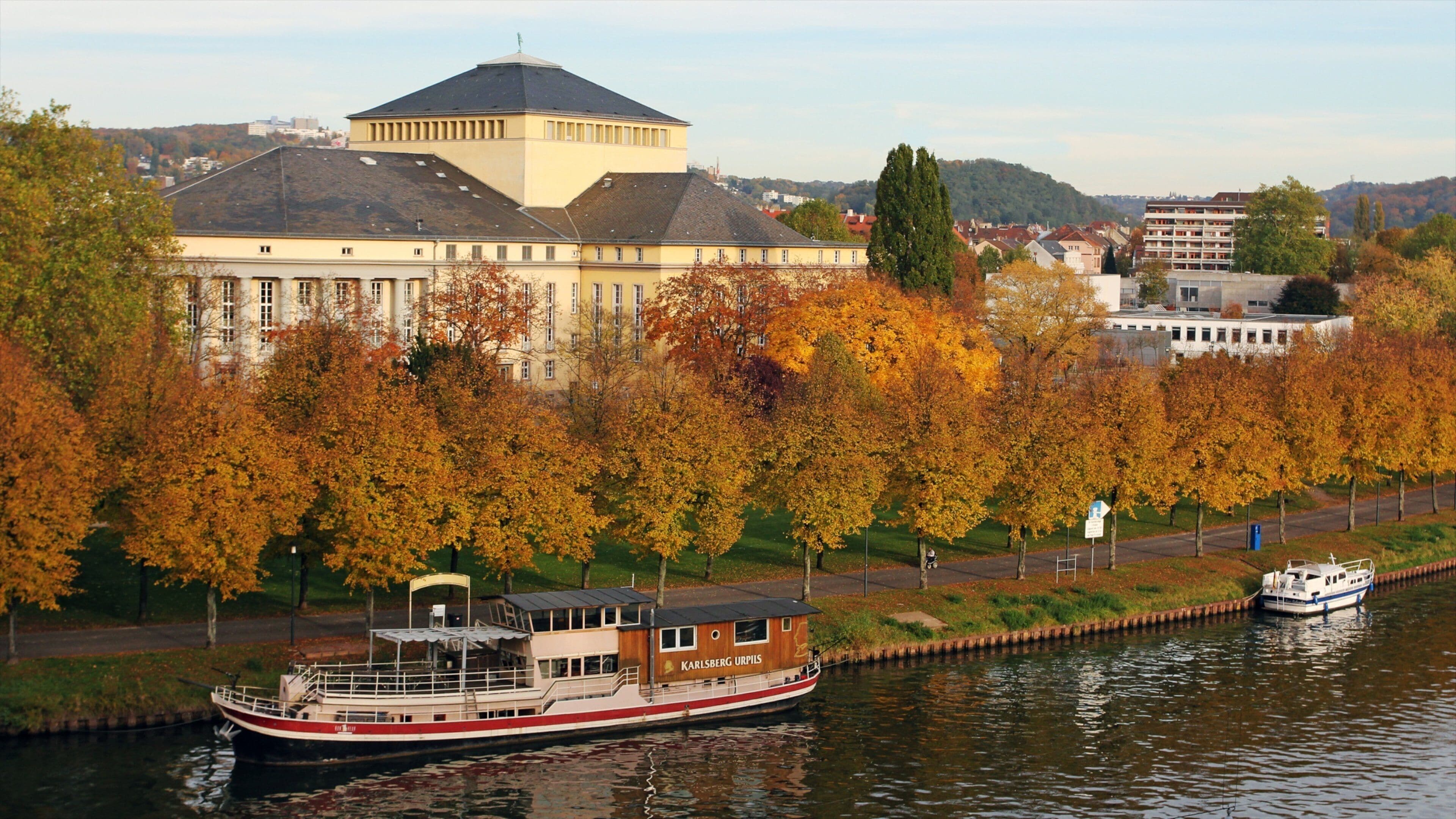 A river with a boat named 'Karlsberg Urpils' and a large building with a dome in the background.