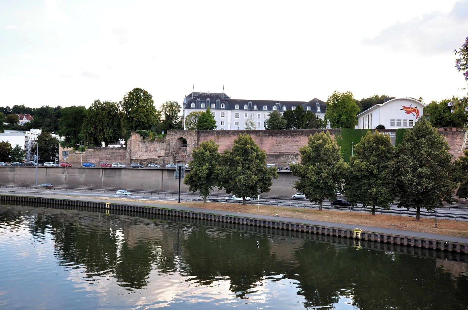 A river with a bridge, trees, and buildings in the background.
