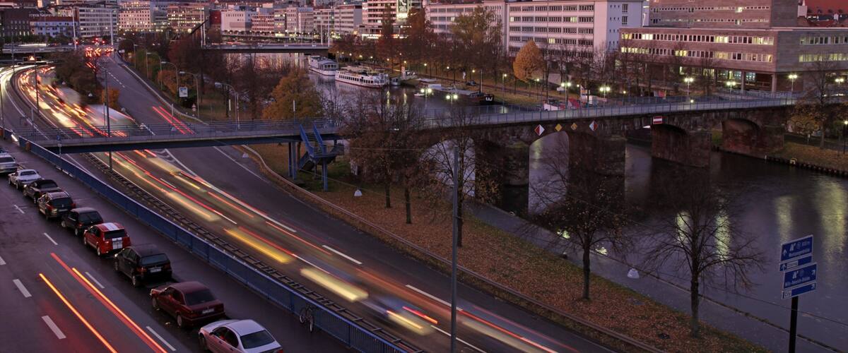 A cityscape with a river, a bridge, and a highway with moving vehicles.