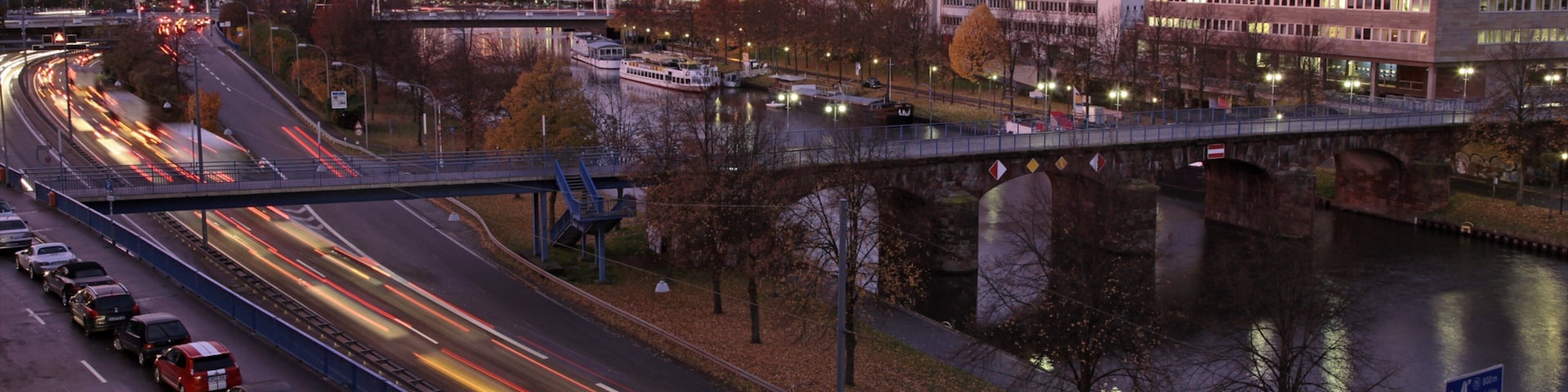A cityscape with a river, a bridge, and a highway with moving vehicles.