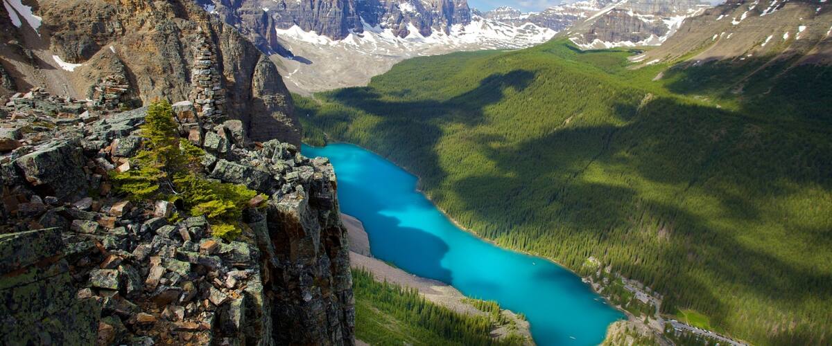 A turquoise lake surrounded by rugged mountains and dense forests.
