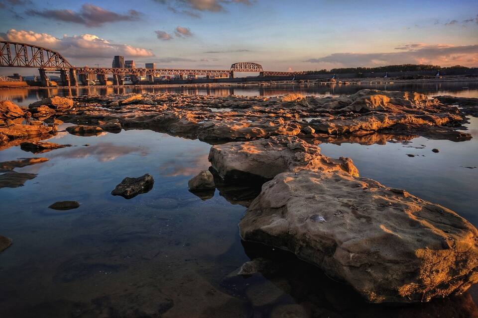 Un fiume con rocce e un ponte sullo sfondo.