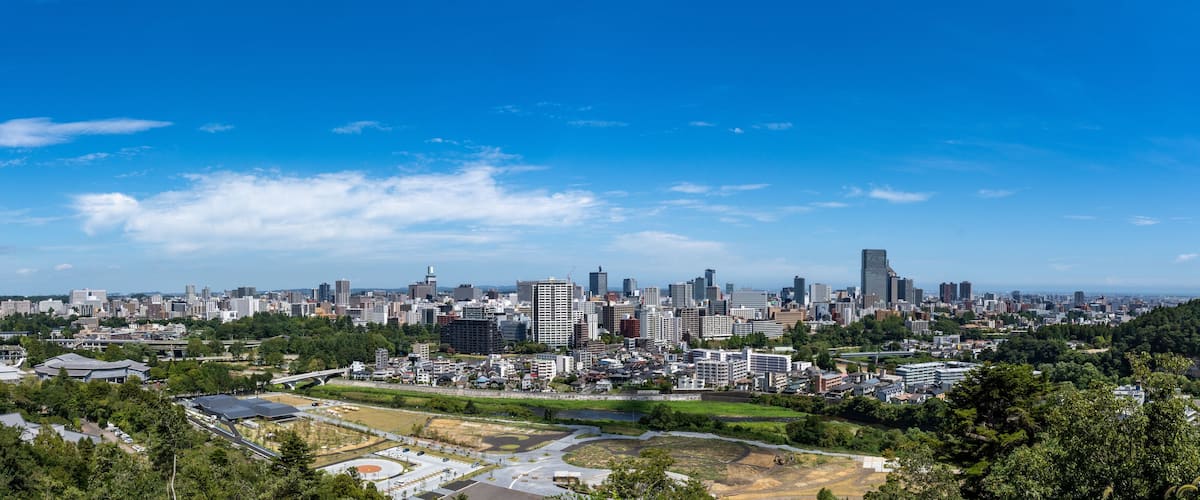 A cityscape with a mix of modern and traditional buildings, a river, and surrounding greenery.