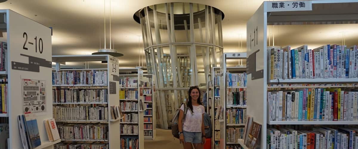 A library interior with bookshelves, a person, and a circular glass structure.