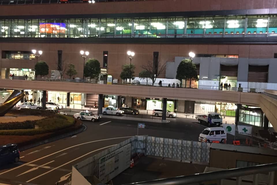 A multi-level station with signage in a foreign language, multiple levels of pedestrian walkways, and various vehicles on the roads.