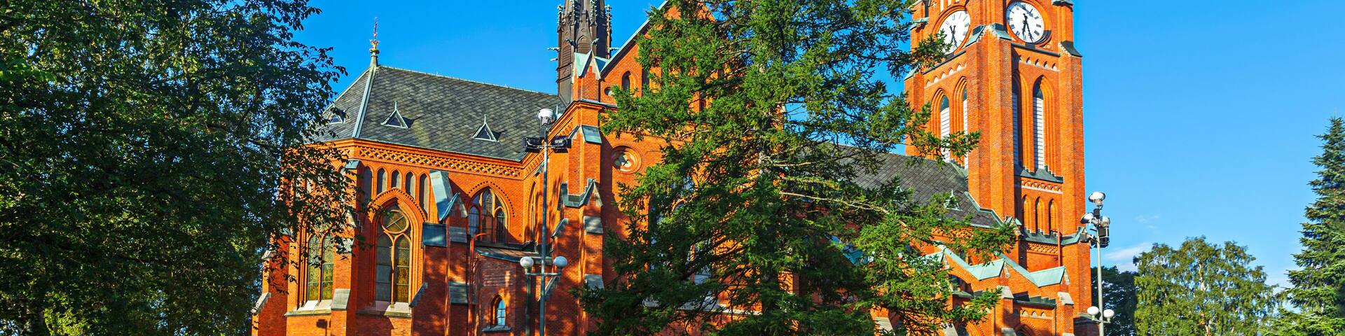 A large brick church with multiple spires and a clock tower.