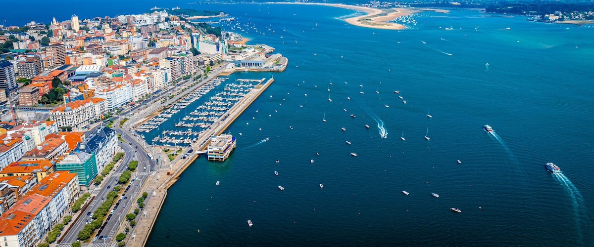 Uma cidade costeira com um porto, barcos e um mar azul cristalino.
