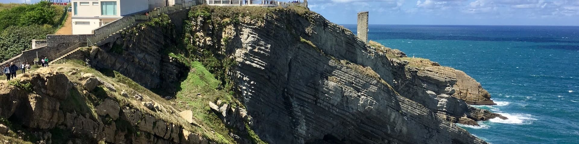 A coastal lighthouse on a rocky cliff, overlooking the ocean.