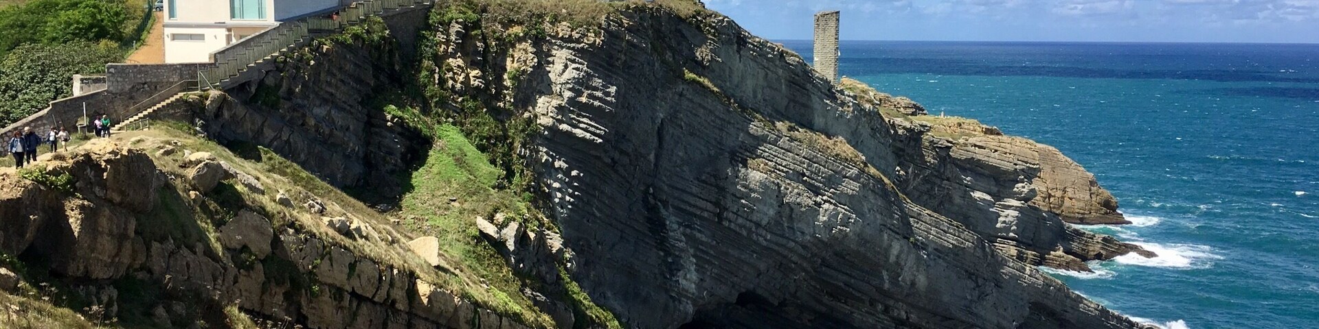 Un faro costero sobre un acantilado rocoso, con vista al océano.