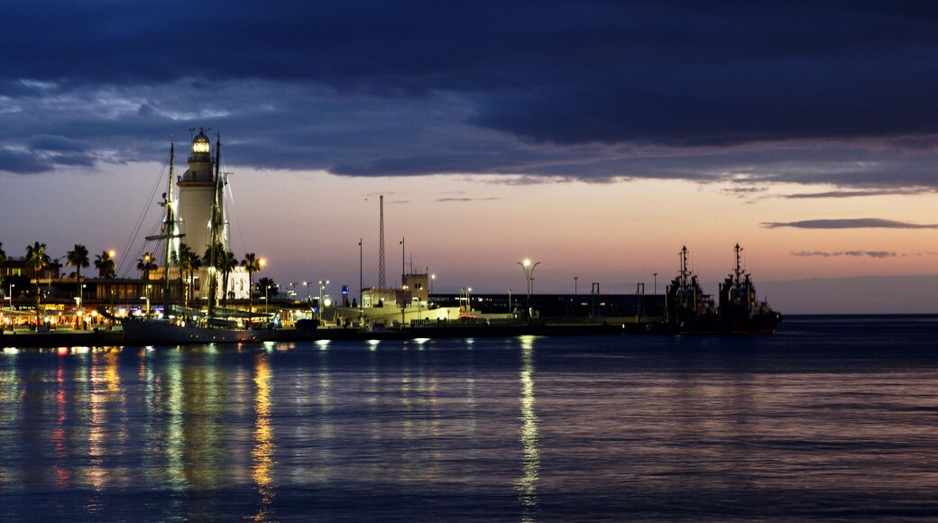 Dusk photo of the lighthouse and harbor in Málaga, Spain.