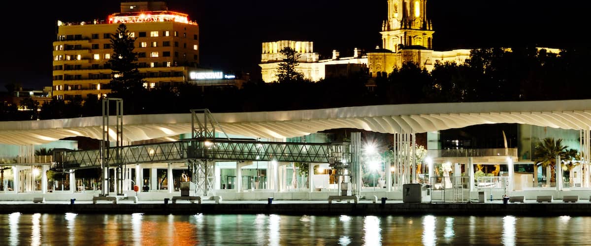 Evening photo of the harbor promenade and Castillo de Gibralfaro, Málaga, Spain.