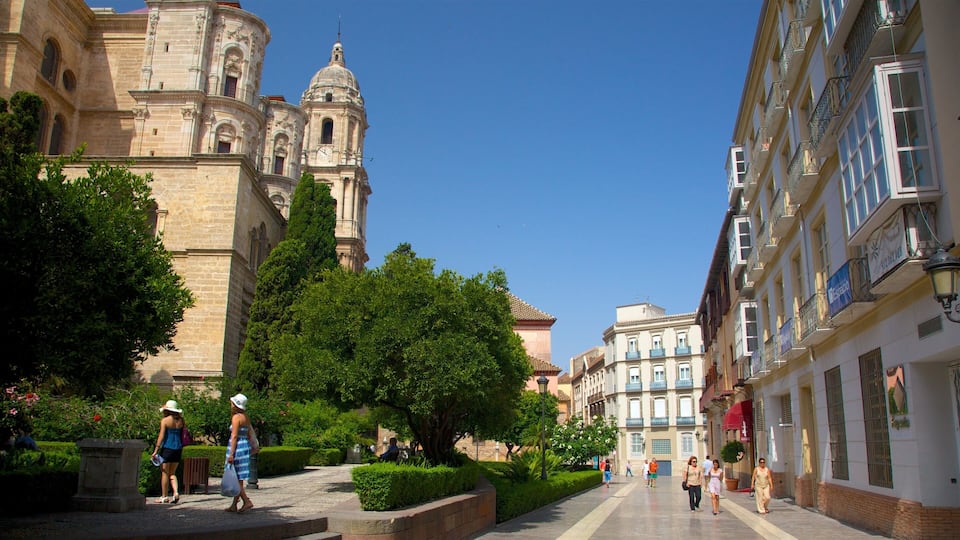 A historic building with a dome and bell towers, surrounded by lush greenery and pedestrians.