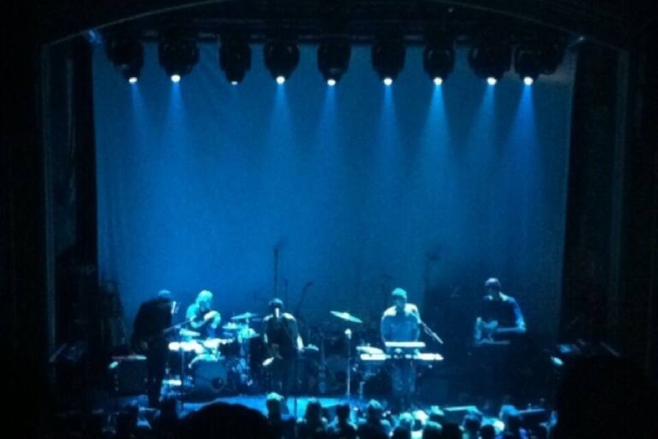 A band performing on a stage with blue lighting.