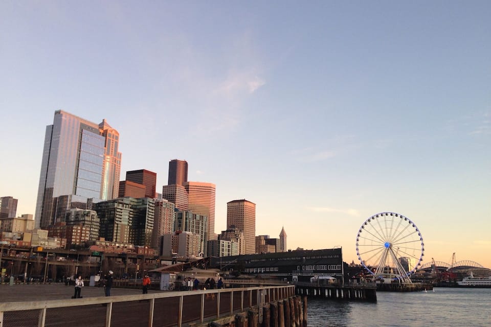 A waterfront cityscape with modern skyscrapers and a large Ferris wheel.