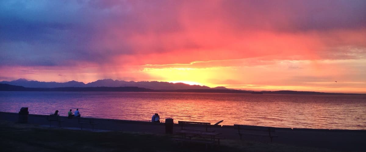 A sunset over a body of water with mountains in the background.